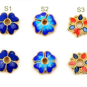 May include: Six gold-coloured flower-shaped beads with enamel paint. Three beads are blue with white accents, and three beads are red with blue accents.