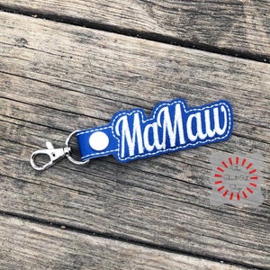 May include: Blue leather keychain with a white embroidered name "MaMaw" on it.