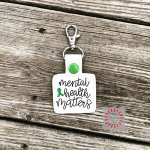 May include: White keychain with a green ribbon and the text "mental health matters".