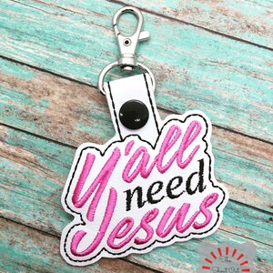 May include: Pink and black embroidered keychain with the text "Y'all need Jesus".