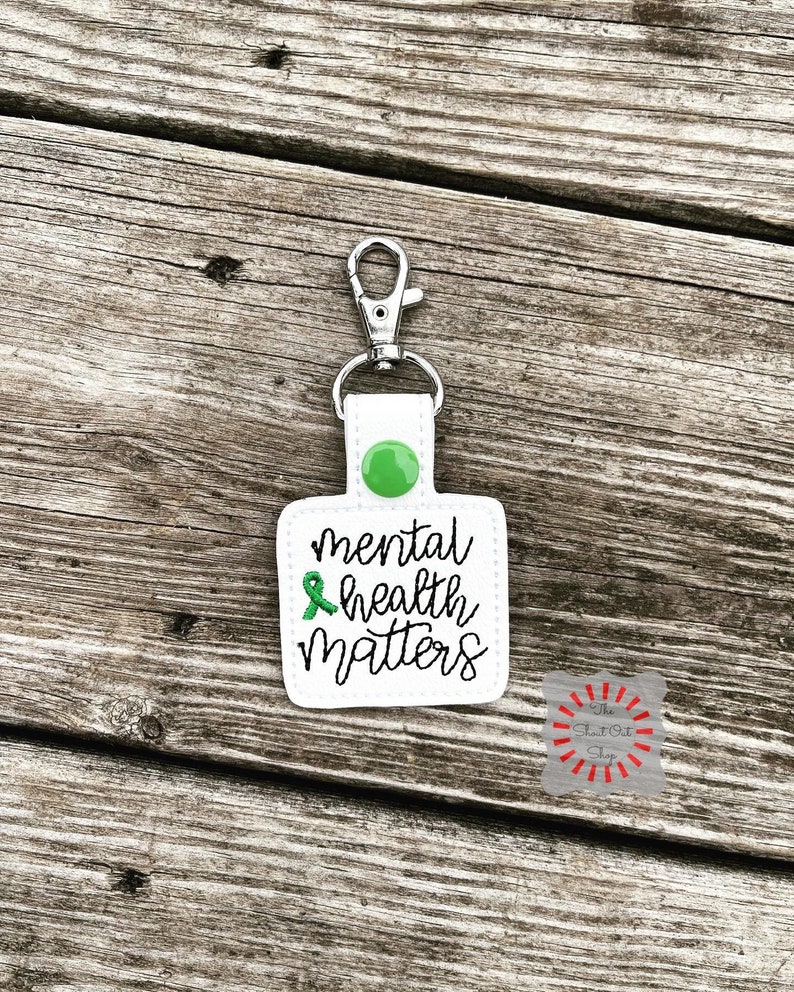 May include: White keychain with a green ribbon and the text "mental health matters".