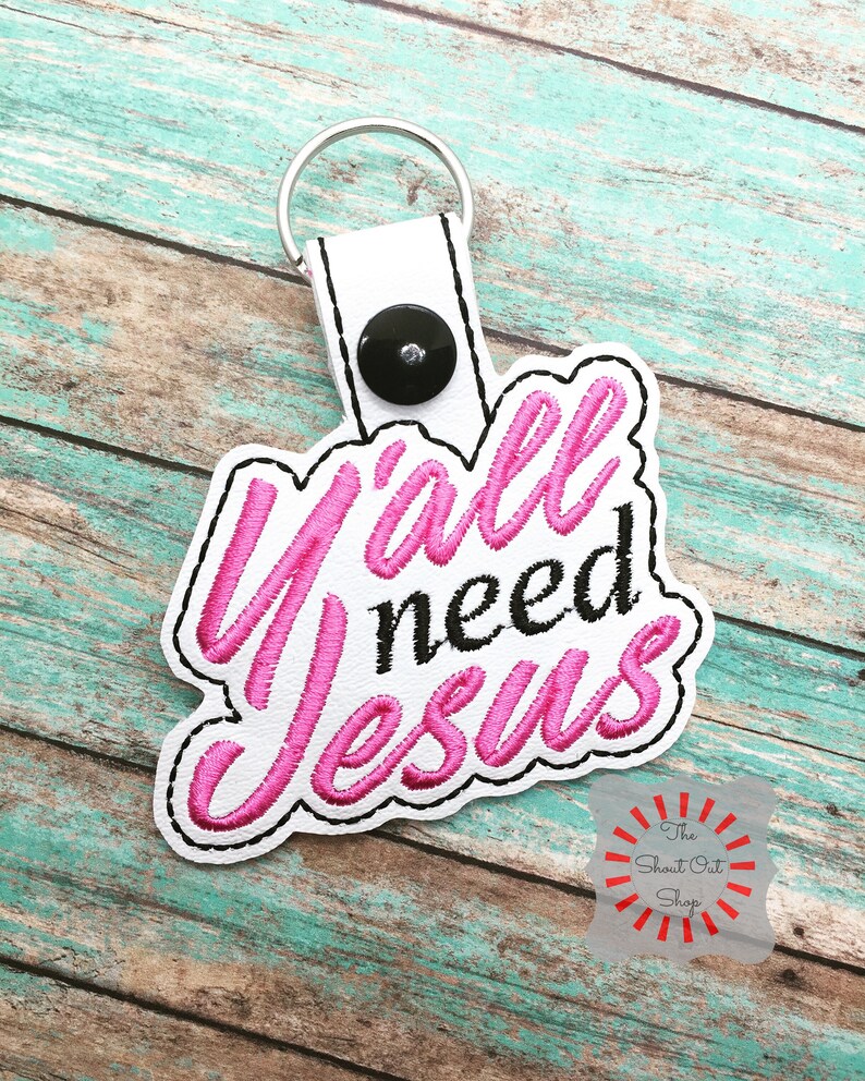 May include: White leather keychain with a pink embroidered phrase "Y'all need Jesus".