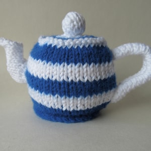 以下が含まれることがあります： 青と白のストライプのニットのティーポットカバー。上部に白いニットのノブが付いています。