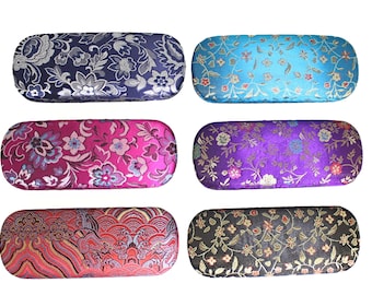 Op de afbeelding: Zes verschillende gepatroneerde brillenetuis. De etuis zijn gemaakt van een zacht, stoffen materiaal en zijn verkrijgbaar in verschillende kleuren en patronen, waaronder blauw, paars, roze, rood en zwart.