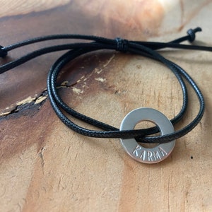 May include: A black cord bracelet with a silver metal charm that says "KARMA" on it.
