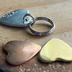 Pu&ograve; includere: Tre etichette di metallo a forma di cuore, una argentata con il nome "Lila" inciso, una di rame e una d'oro.