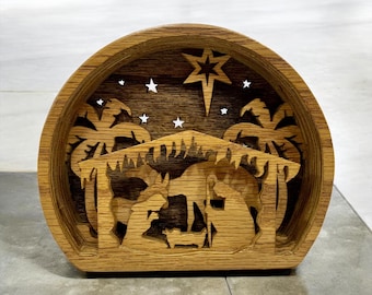 May include: A wooden nativity scene, featuring a layered design with a star, palm trees, and silhouettes of figures. The piece is crafted from light brown wood, with a semi-circular shape and a flat base. The design includes stars and a central star.