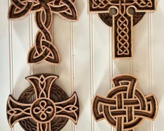 May include: Four wooden Celtic cross wall decor pieces in various designs. The crosses are intricately carved with knotwork patterns and have a dark brown stain.