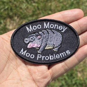 May include: A black embroidered patch with a cartoon hippopotamus and the text "Moo Money Moo Problems".