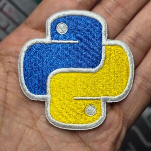 May include: A blue and yellow embroidered Python logo patch. The patch has a white outline and is perfect for adding a touch of coding flair to your belongings.