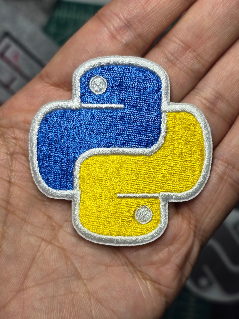 May include: A blue and yellow embroidered Python logo patch. The patch has a white outline and is perfect for adding a touch of coding flair to your belongings.