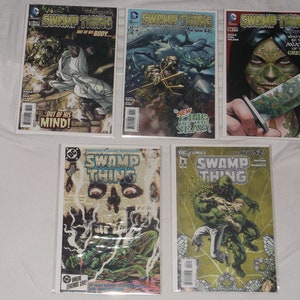 May include: A collection of five comic books featuring Swamp Thing, a DC Comics superhero. The covers feature various illustrations of Swamp Thing in different scenarios, including a skull, a creature in the water, and a woman with a knife.