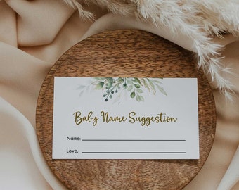 Puede incluir: Una tarjeta blanca con follaje verde y el texto "Baby Name Suggestion" en letras doradas. La tarjeta tiene líneas para escribir un nombre y un mensaje.
