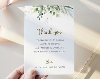 Puede incluir: Una tarjeta de agradecimiento blanca con follaje verde y dorado y el texto "Gracias" en letras doradas. La tarjeta dice "Ustedes trajeron alegría a nuestro día, calidez a nuestras vidas y felicidad a nuestros corazones. Gracias por su regalo especial! Con amor, Olivia, James y la bebé Emma."