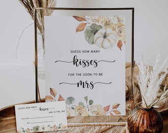 Puede incluir: Un cartel enmarcado en dorado con un diseño floral de acuarela en tonos amarillos, verdes y naranjas. El cartel dice "Adivina cuántos besos para la futura Sra."
