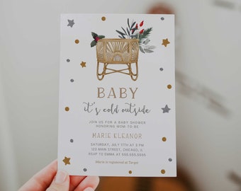 May include: Baby shower invitation with a watercolor illustration of a wicker bassinet, greenery, and gold stars. The text reads "Baby it's cold outside" and includes event details for Marie Eleanor.