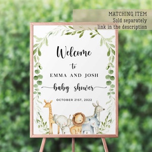 May include: Welcome to Emma and Josh's baby shower sign with a leafy green border and a watercolor illustration of a giraffe, elephant, lion, zebra, and rhinoceros. The sign says "Welcome to Emma and Josh baby shower October 21st, 2022".