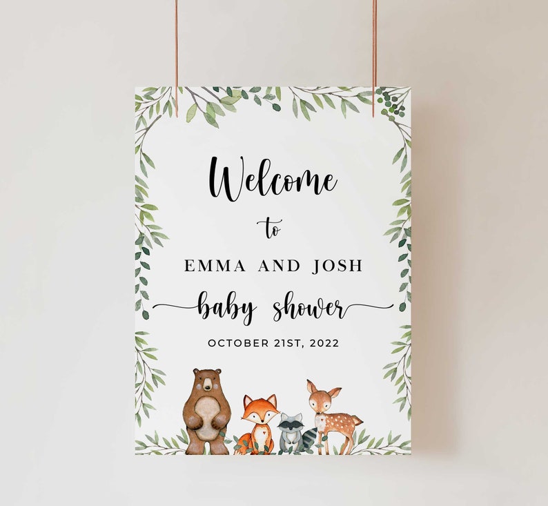 May include: Welcome to Emma and Josh's baby shower sign with a leafy green border and woodland animal illustrations. The sign says "Welcome to Emma and Josh baby shower October 21st, 2022".