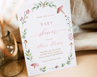 Puede incluir: Una invitación de baby shower blanca con un borde de corona floral. El texto dice "Por favor, únase a nosotros para una Baby Shower en honor a Marie Eleanor. Sábado, 17 de julio a las 3 pm, 123 Main Street, Chicago, IL. RSVP a Emma al 555.555.5555. Marie está registrada en Target."