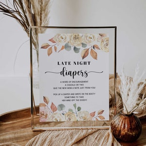 May include: A framed sign with the words "LATE NIGHT diapers" in elegant script. The sign is decorated with watercolor floral elements in shades of yellow, peach, and brown. The text below offers suggestions for diaper changes.