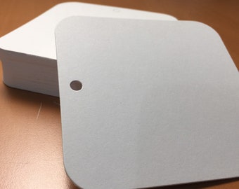 May include: A stack of white square cards with rounded corners. The top card has a hole punched in the center.