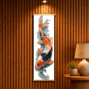 May include: A vertical wall hanging featuring a detailed illustration of a koi fish with orange, white, and black scales swimming through stylized grey water currents. The artwork is mounted on a light wooden frame with a string for hanging.