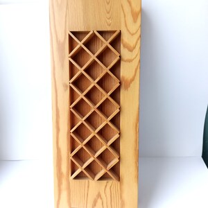 Könnte beinhalten: Eine Holzlampe mit einem rautenförmigen Ausschnitt. Die Lampe ist aus hellbraunem Holz gefertigt und hat ein schlichtes, modernes Design.