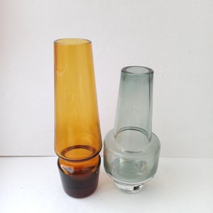 May include: Two glass vases, one amber and one grey, with a flared top and a wider base.