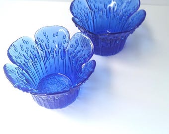 以下が含まれることがあります： 青いガラスの花の形をしたボウルが2つ。ボウルは表面がテクスチャ加工されており、小さなスナックやデザートを提供するのに最適です。