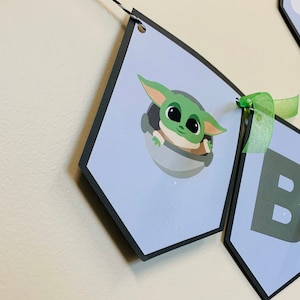 May include: A blue and green banner with the words "Baby Yoda" and a picture of Baby Yoda in a spaceship.