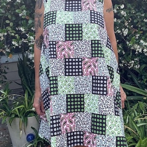 May include: A sleeveless patchwork dress featuring a mix of paisley and geometric patterns in black, white, pink, and green. The dress has a scoop neckline and a slightly asymmetrical hemline, creating a unique and eye-catching design.