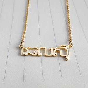 Puede incluir: Collar de oro con un colgante de placa con la palabra tailandesa "เสกุน" en un estilo moderno y minimalista.