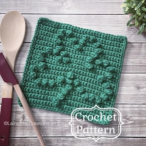 Może przedstawiać: Zielony podkładka pod gorące na szydełku z fakturowanym wzorem. Podkładka leży na drewnianej powierzchni z tekstem "Crochet Pattern" poniżej.
