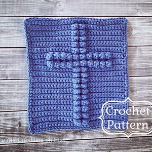 May include: A crochet pattern for a blue cross with a textured design. The pattern is written in white text on a white background.