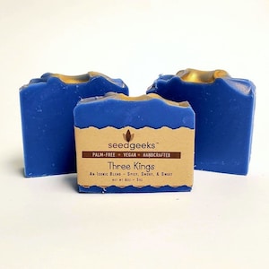 May include: Three bars of blue soap with gold accents. The soap is labelled "seedgeeks" and "Three Kings". The label also states that the soap is palm-free, vegan, and handcrafted. The soap is an iconic blend of spicy, smoky, and sweet scents. The soap weighs 120 g.