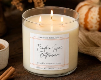 May include: A three-wick candle in a clear glass jar with a white label reading Seedgeeks Candle Co. Pumpkin Spice Buttercream, pumpkin cinnamon cream, 100% soy wax candle, 17 oz. The wax is off-white and the label has orange borders.