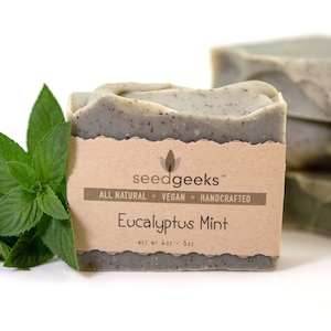 May include: A rectangular bar of Eucalyptus Mint soap with a brown paper label. The label reads "seedgeeks" and "Eucalyptus Mint". Fresh green mint leaves are on the left. The soap weighs 4oz - 5oz.