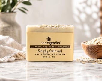 May include: A bar of Simply Oatmeal soap by seedgeeks, with the text "All Natural, Unscented, Handcrafted". The soap is light yellow with oatmeal flakes on top. A wooden bowl of oats is in the background. Net weight is 4 oz - 5 oz.
