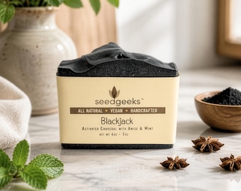 May include: A rectangular bar of black activated charcoal soap wrapped in a beige paper label. The label reads seedgeeks, All Natural, Vegan, Handcrafted, Blackjack, Activated Charcoal with Anise & Mint, and Net Wt 4oz - 5oz in black text.