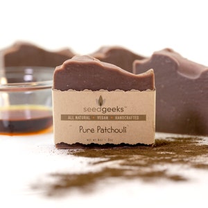 May include: Close-up of several bars of brown soap with a textured surface. Each bar is wrapped with a brown paper label that reads "Pure Patchouli" and "seed geeks". A small bowl of liquid is in the background. The soap bars are 4 oz - 5oz.