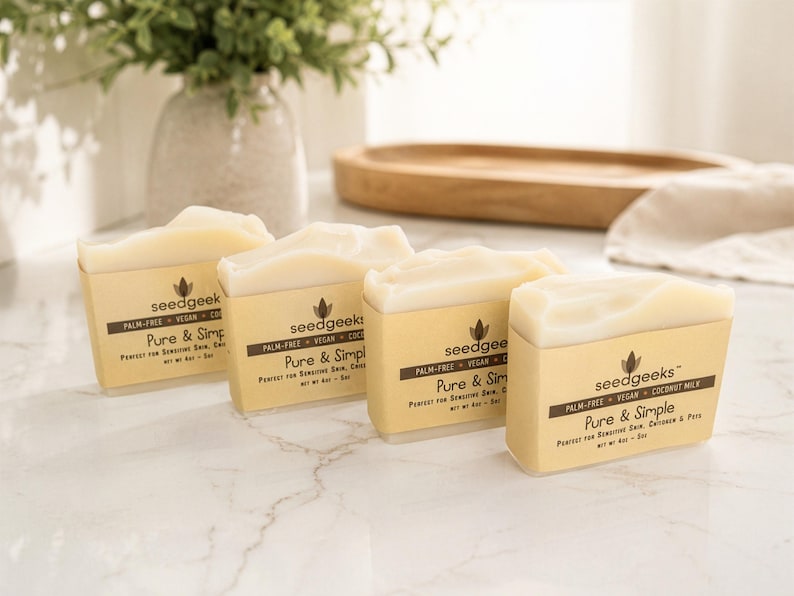 May include: Four rectangular bars of off-white soap wrapped in tan paper bands. Each band features the text seedgeeks, palm-free, vegan, coconut milk, Pure & Simple, and net wt 4oz. The soap bars are arranged in a diagonal line on a white surface.