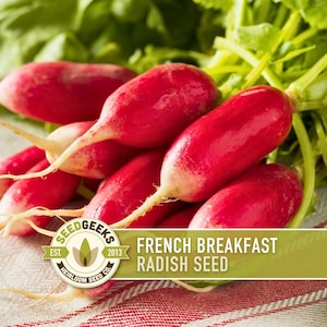 a bunch of fresh radishes with their roots visible, arranged on a cloth. The radishes appear to be red and have a vibrant color. The image also includes text that reads "French Breakfast Radish Seed" and "SEEDGEEKS EST. 2013 HERROMOM SEEDS CO."