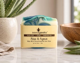 May include: A rectangular bar of soap with a marbled blue, green, and white top. The label reads seedgeeks, Palm-Free, Vegan, Handcrafted, Aloe & Agave, Made With Fresh, Hydrating Aloe Vera, and Net Wt 4oz - 5oz in black text on a tan background.