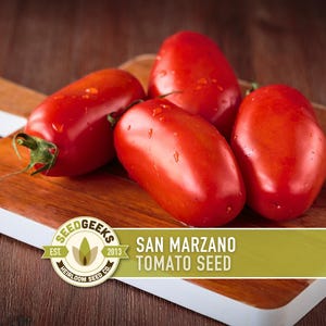Puede incluir: Cuatro tomates San Marzano rojos y maduros, con gotas de agua, descansan sobre una tabla de cortar de madera. Los tomates son oblongos y brillantes, con tallos verdes. El texto "San Marzano Tomato Seed" y un logotipo están incluidos.