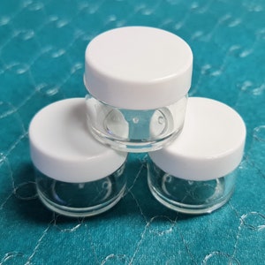 May include: Three clear plastic jars with white lids. The jars are stacked on top of each other.