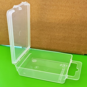 May include: A clear plastic storage box with a hinged lid and a carrying handle. The box has a small, clear circle on the front and the text "MADE IN CHINA" printed on the side.