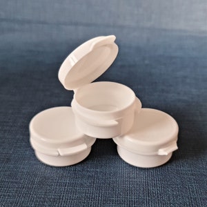 May include: Three white plastic containers with lids. The lids are hinged and have a small lip on the side. The containers are stacked on top of each other.