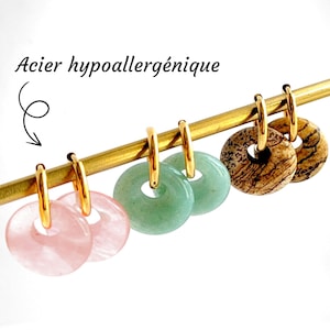 Peut inclure: Boucles d'oreilles créoles dorées avec des pendentifs circulaires en pierres précieuses roses, vertes et marron. Elles sont suspendues à une tige dorée. Le texte "Acier hypoallergénique" est en haut et "Hypoallergenic steel" en bas.