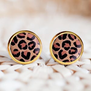 Peut inclure: Une paire de boucles d'oreilles clous dorées avec un motif léopard. Les boucles d'oreilles sont rondes et ont une finition brillante.