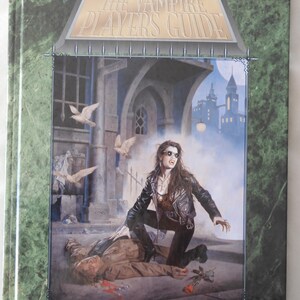 May include: A book cover for "The Vampire Players Guide" featuring a dramatic illustration. A woman in a leather jacket kneels over a figure on the ground, with a city and flying doves in the background. The book has a green marble-like border.